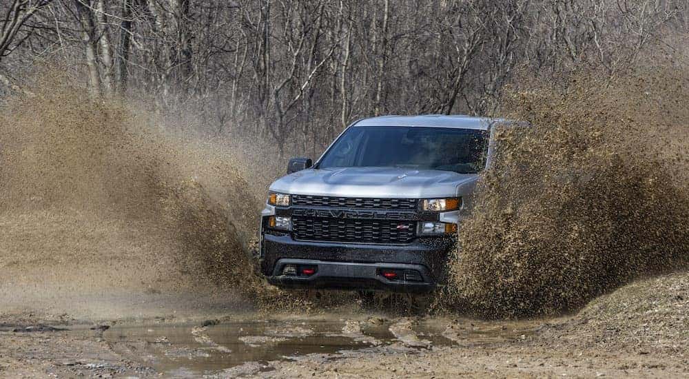 A silver 2020 Chevy Silverado 1500 Z71 Trail Boss is shown from the front while driving through mud.