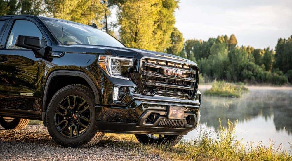 A close up shows the front of a black 2020 GMC Sierra 1500 SLE Elevation parked near a lake.