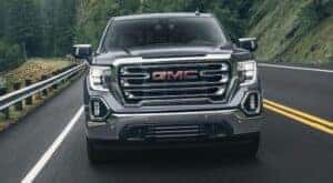 A grey 2022 GMC Sierra 1500 is shown from the front driving on an open road.