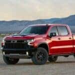 Popular used trucks for sale, a red 2022 Chevy Silverado 1500 ZR2, is shown parked on sand.