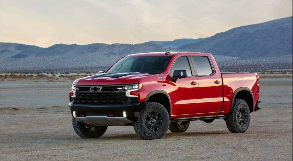 Popular used trucks for sale, a red 2022 Chevy Silverado 1500 ZR2, is shown parked on sand.