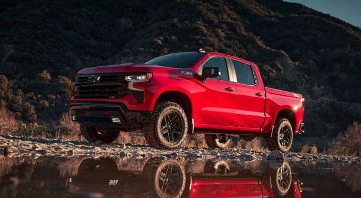 A red 2023 Chevy Silverado 1500 Z71 Trail Boss is shown from the side while off-road after leaving a dealer that has a Chevy Silverado for sale.