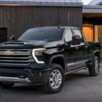 A black 2024 Chevy Silverado 2500 HD High Country is shown parked on a driveway after viewing a Chevy Silverado for sale.