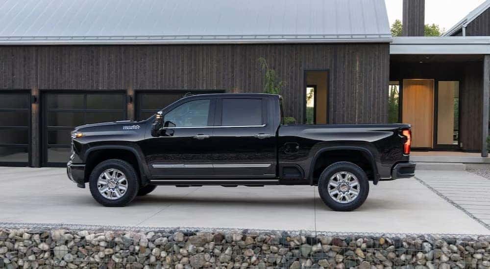 A black 2024 Chevy Silverado 2500 HD High Country is shown parked near a house.
