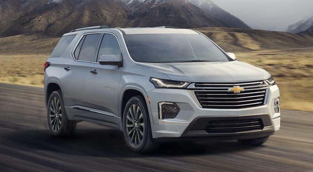 A white 2022 Chevy Traverse is shown driving near a mountain.