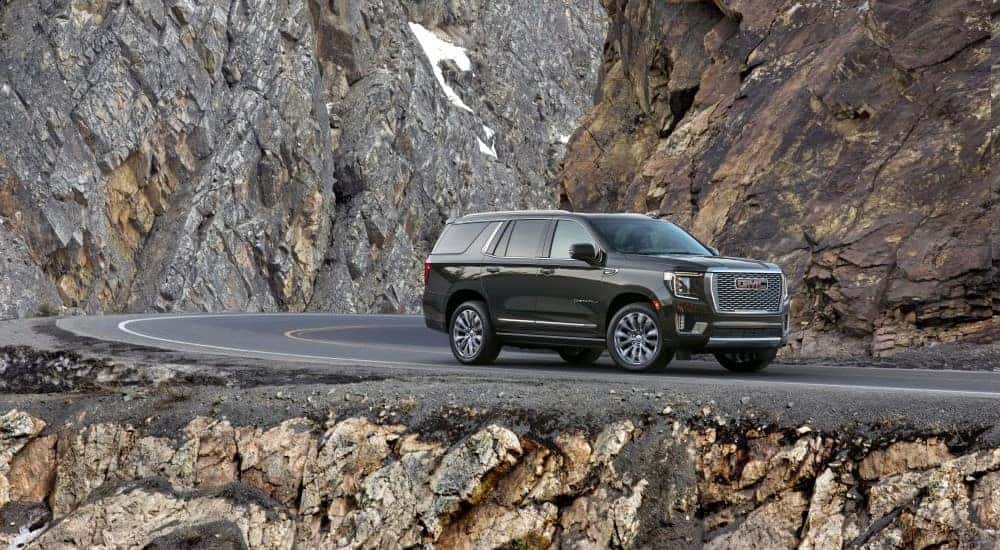 A black 2021 GMC Yukon Denali is shown driving a mountain road.
