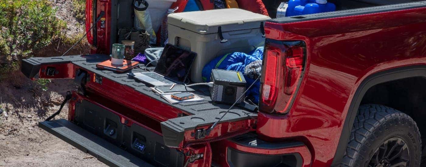 A close up of the bed of a red used 2022 GMC Sierra AT4X for sale is shown full of camping gear.