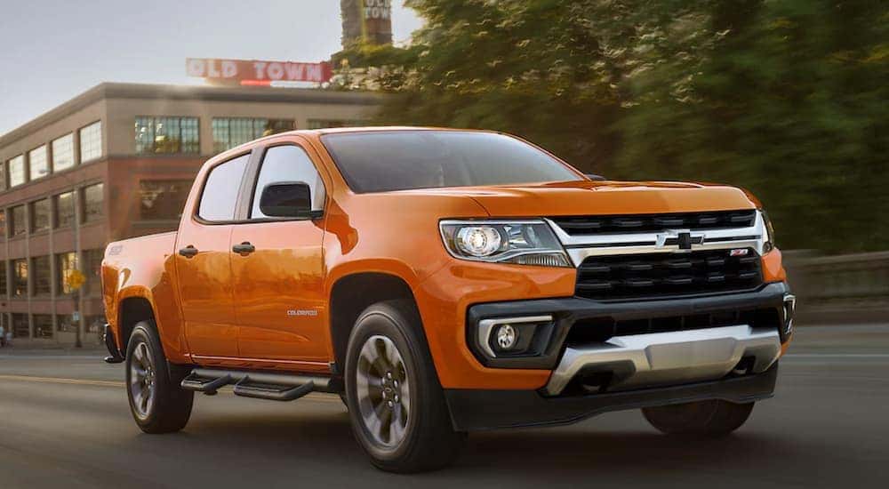 An orange 2021 Chevy Colorado Z71 is shown driving on a city street.