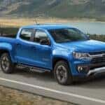 A popular used Chevy Colorado for sale, a blue 2022 Chevy Colorado Z71, is shown driving on a highway.