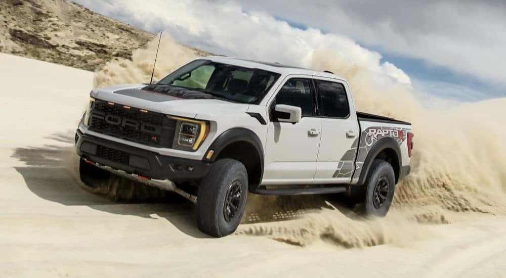 A white 2023 Ford F-150 Raptor R is shown driving off-road.