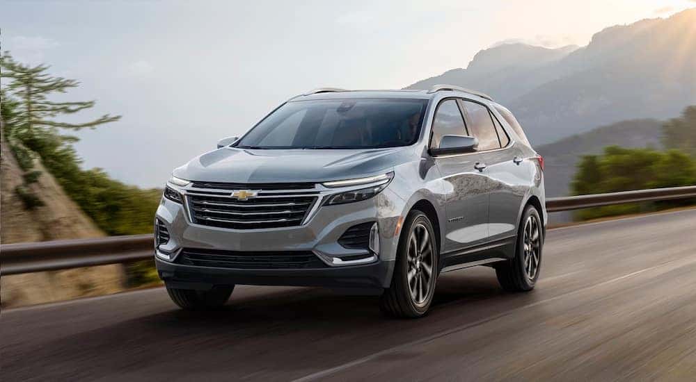 A silver 2024 Chevy Equinox is shown driving from a Chevy dealer near Midvale.