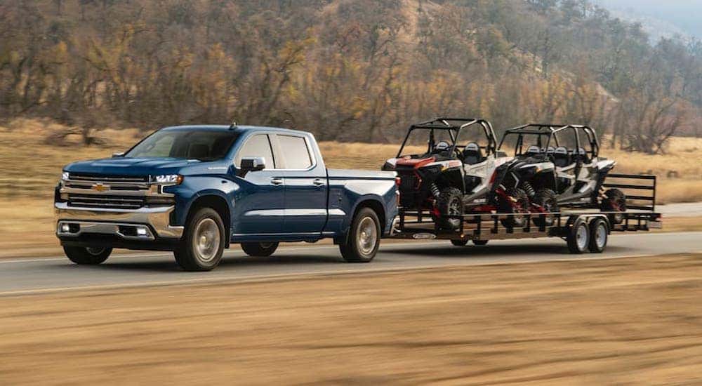 A blue 2024 Chevy Silverado 1500 is shown towing some carts.