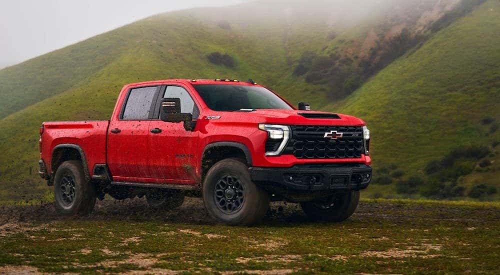 A red 2024 Chevy Silverado 2500HD ZR2 is shown parked off-road in a valley.
