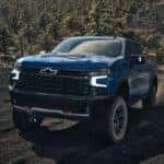 A blue 2024 Chevy Silverado 1500 ZR2 is shown driving off-road after visiting a dealer with a Chevy Silverado for sale near Alpine, UT.