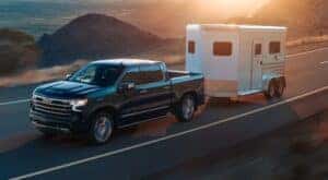 A black 2024 Chevy Silverado 1500 ZR2 is shown towing a trailer from a dealer with a Chevy Silverado for sale near Kearns.