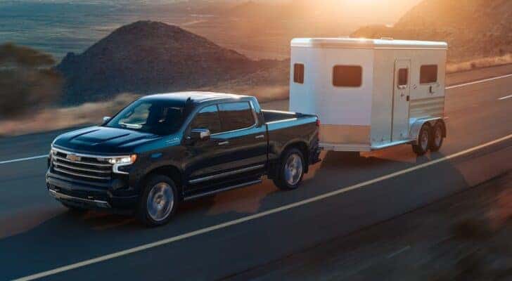 A black 2024 Chevy Silverado 1500 ZR2 is shown towing a trailer from a dealer with a Chevy Silverado for sale near Kearns.