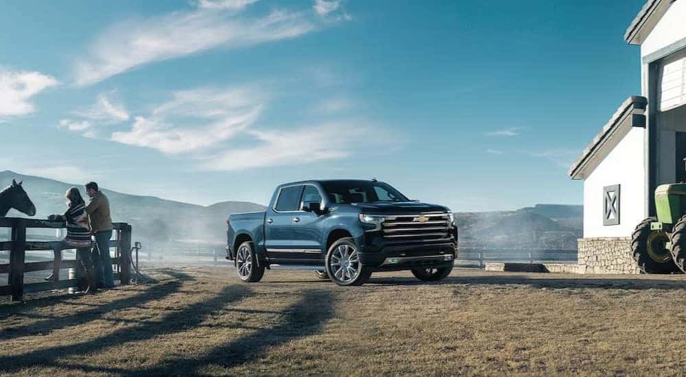 A blue 2024 Chevy Silverado LT High Country is shown parked on a ranch.