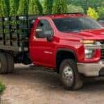 A red 2023 Chevy Silverado 3500HD is shown parked near many plants after viewing used trucks for sale near Sandy.