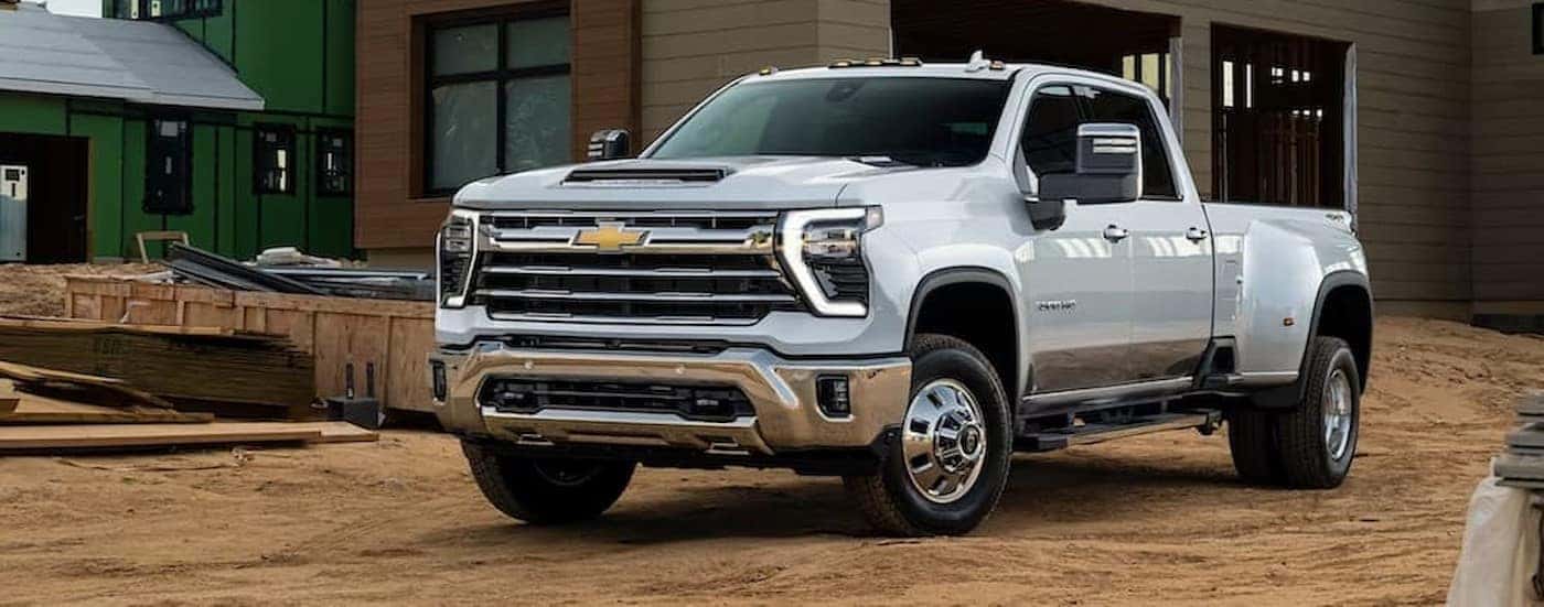 A white 2024 Chevy Silverado 2500 HD is shown parked near a construction site.