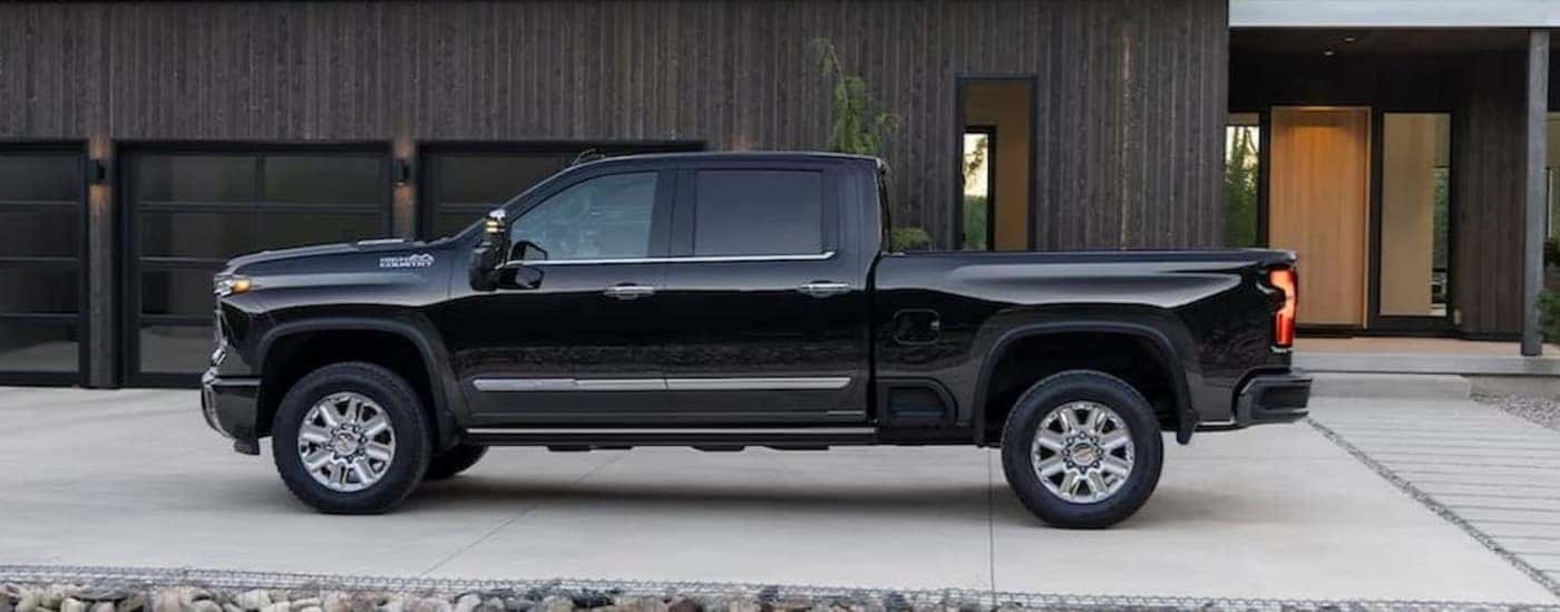 A black 2024 Chevy Silverado 3500 HD High Country is shown parked near a house.
