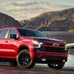 A red 2024 Chevy Silverado 1500 Z71 RST is shown parked near a boat.