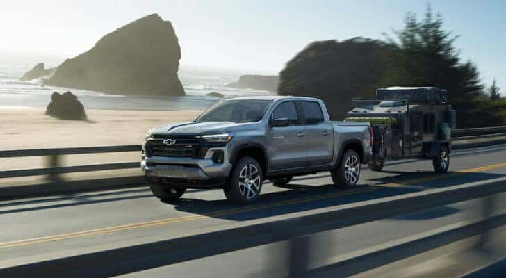 A silver 2024 Chevy Colorado Z71 towing a camper.