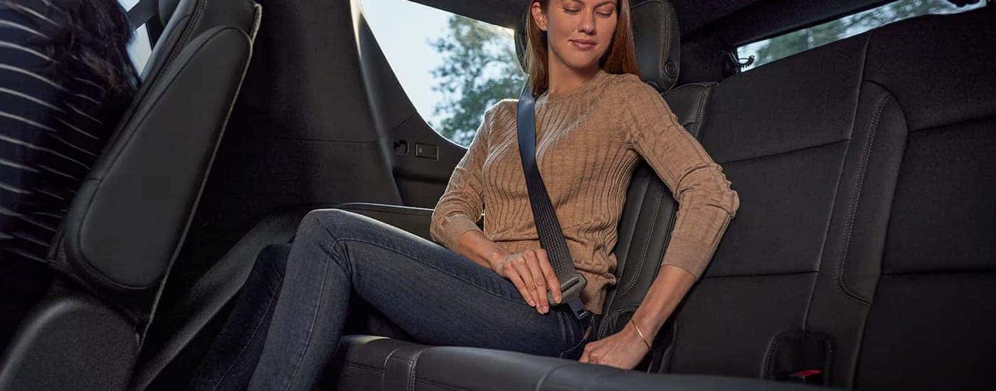 A woman is buckling into the back seat of a 2025 Chevy Tahoe.