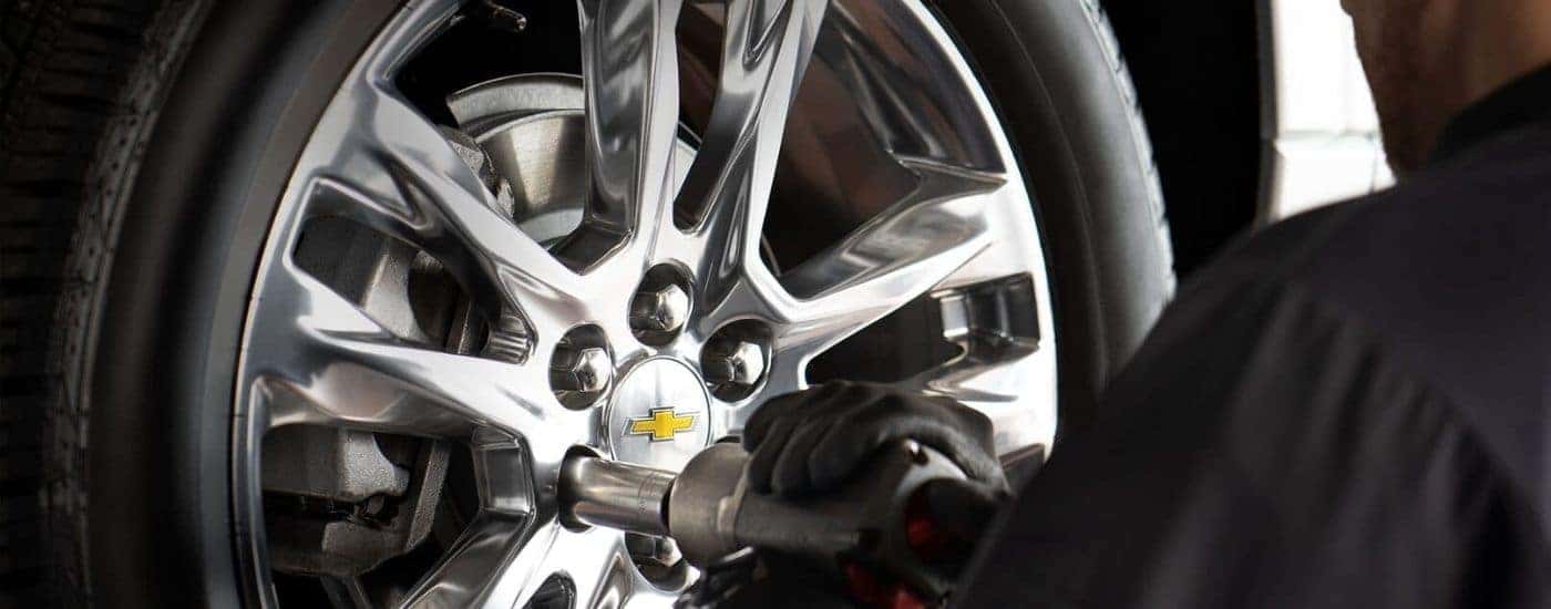 A close up shows a tech installing a tire.