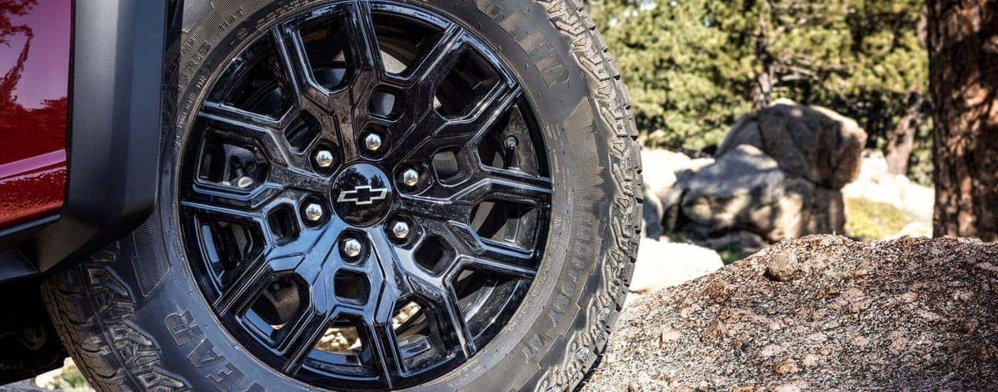 A close up shows the wheel and tire on a red 2023 Chevy Colorado.