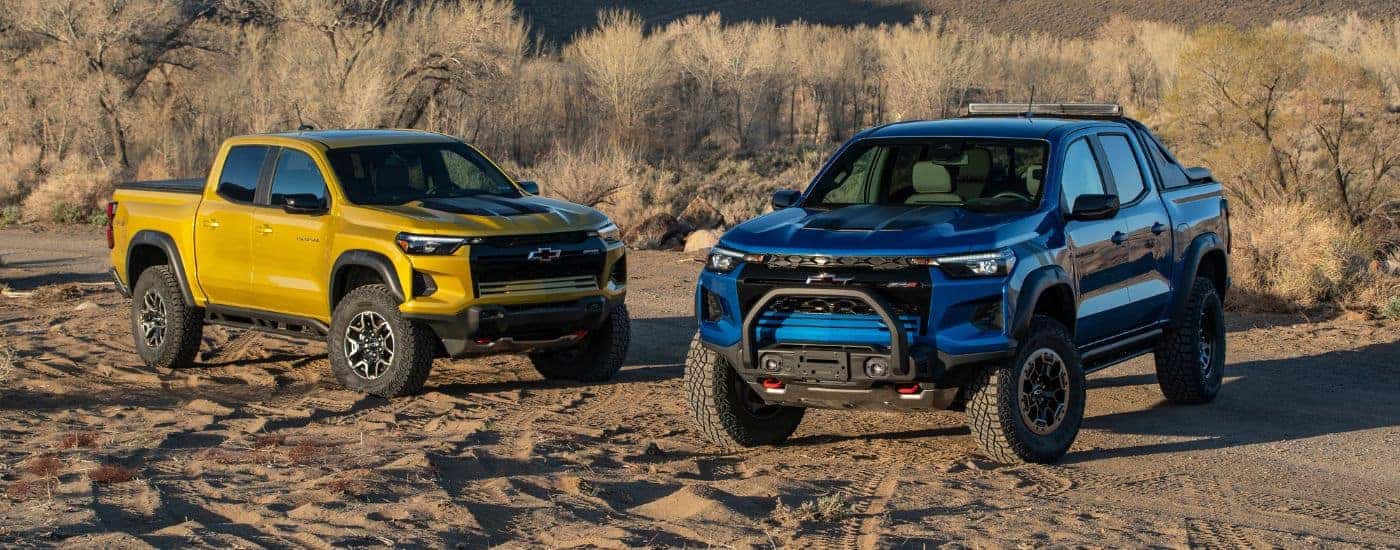 A yellow 2023 Chevy Colorado ZR2 and a blue ZR2 Desert Boss are shown off-road.