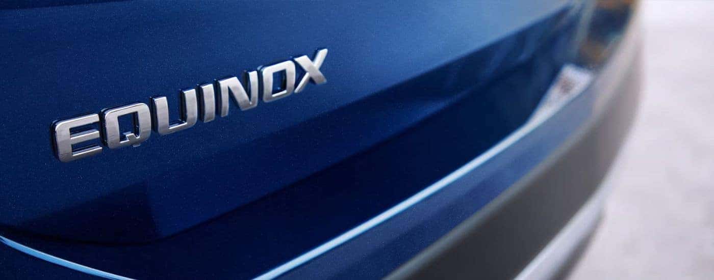 A close up shows the "Equinox" badge on a blue 2023 Chevy Equinox.