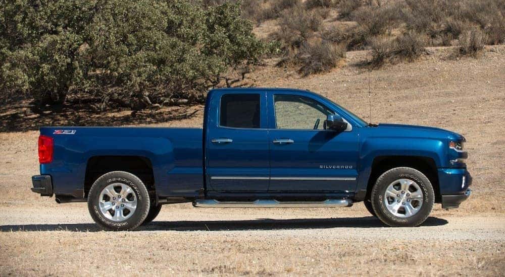 One of many popular used trucks for sale, a blue 2018 Chevy Silverado 1500 Z71, is shown parked off-road.