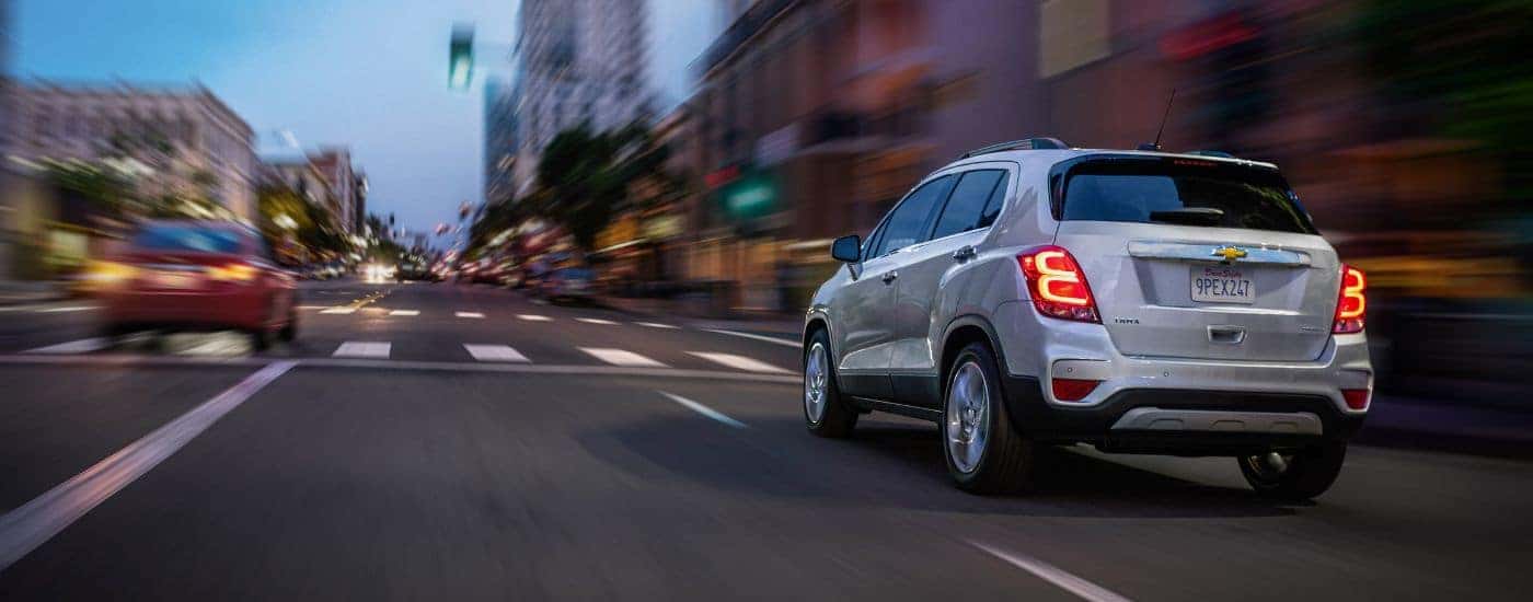 A silver 2020 Chevy Trax Premier is shown driving through an intersection.