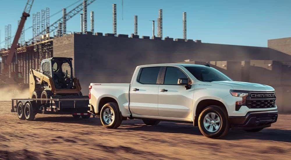 A white 2022 Chevy Silverado 1500 is shown towing a trailer.
