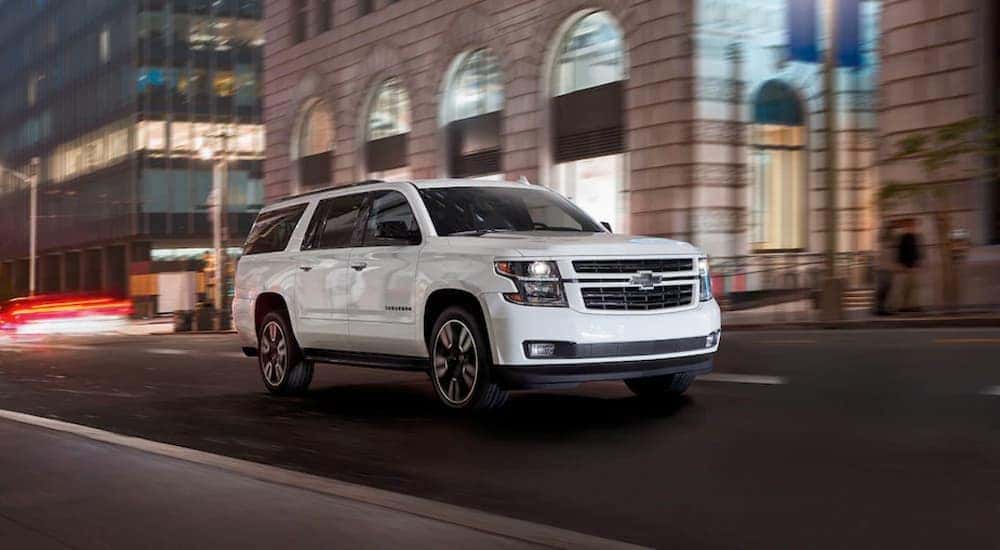 A white 2019 Chevy Suburban for sale is shown driving on a city street.