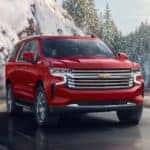 A red 2025 Chevy Suburban driving around a bend.