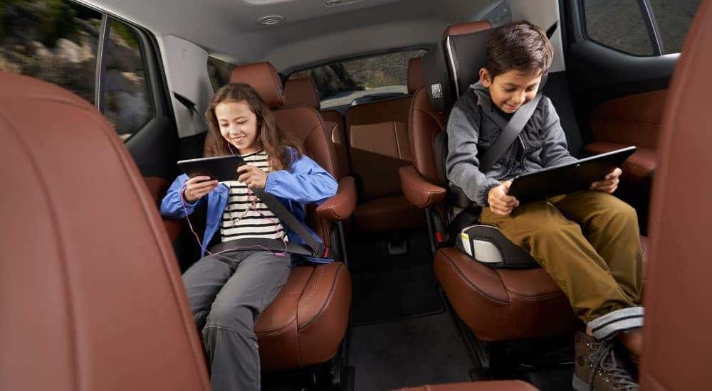 Two children are shown sitting on the brown interior in a 2018 Chevy Traverse.