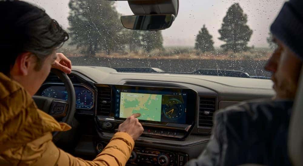 A person is shown using the infotainment screen in a 2025 Chevy Silverado 1500.