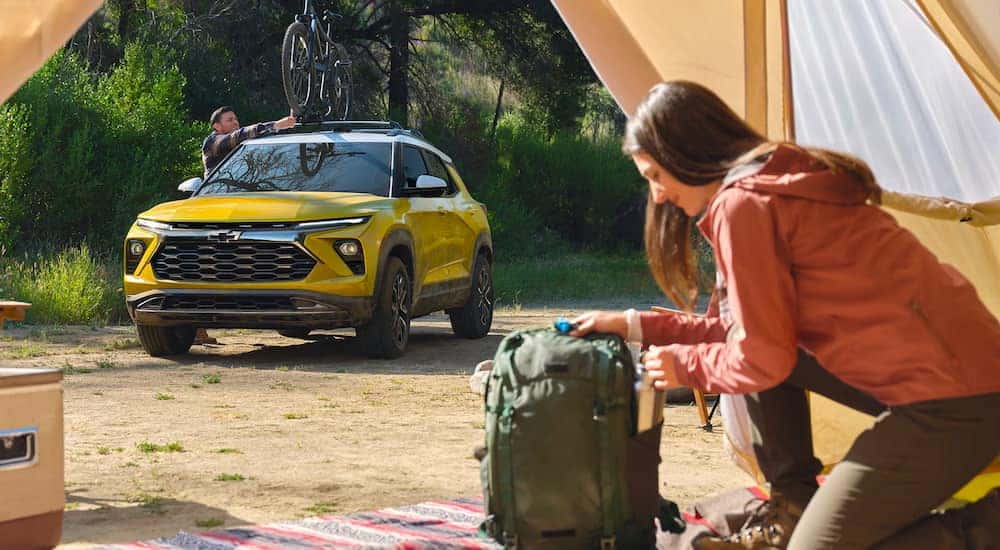 A yellow 2025 Chevy Trailblazer parked by a camp.