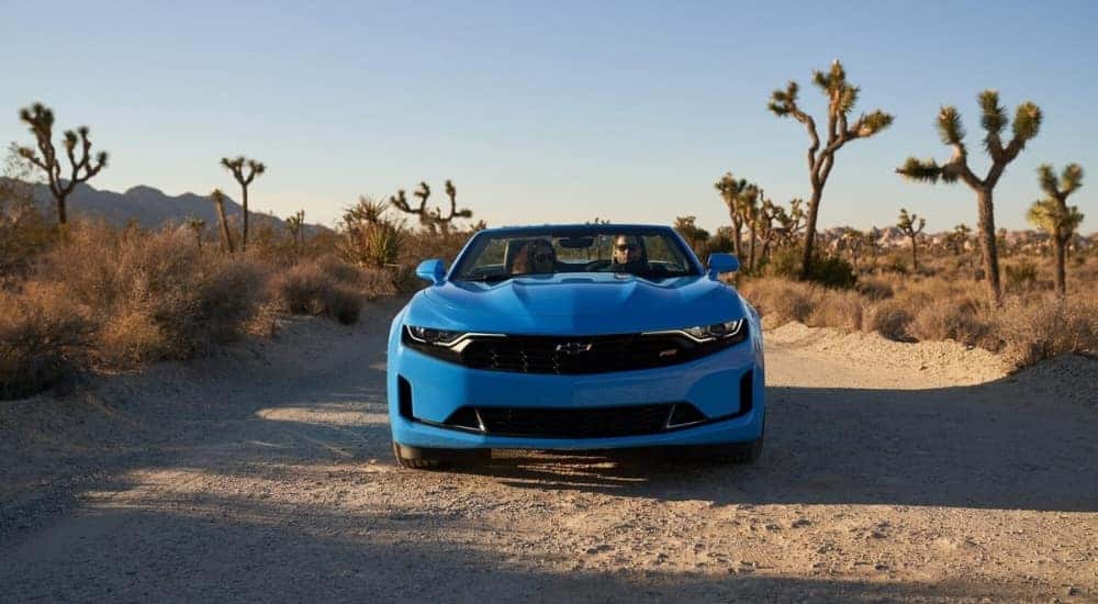 A blue 2023 Chevy Camaro RS is shown on a dirt path.