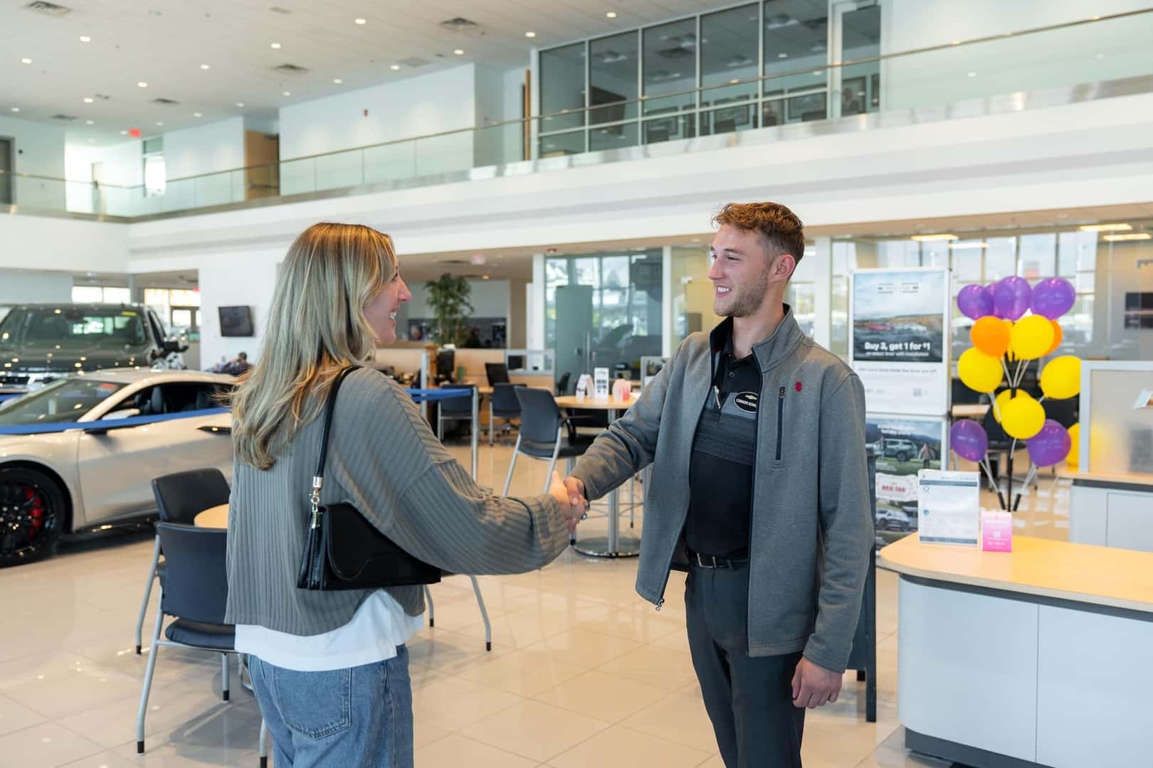 Two people speaking next to finance desk inside dealership