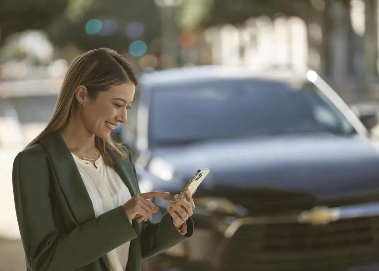 An exterior shot of a vehicle being appraised online by a woman with a phone