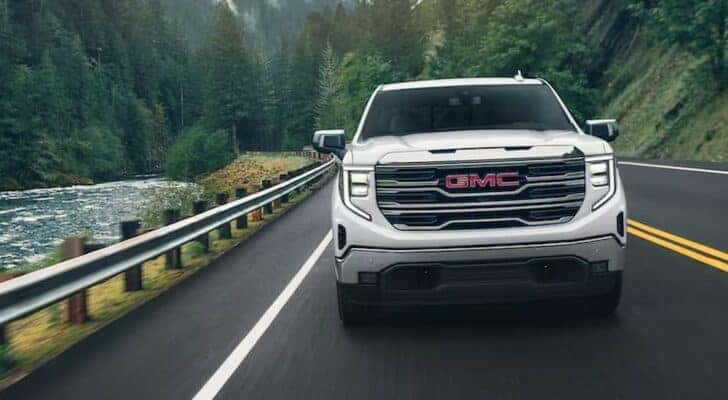 A white 2024 GMC Sierra 1500 Pro is shown driving on a highway.