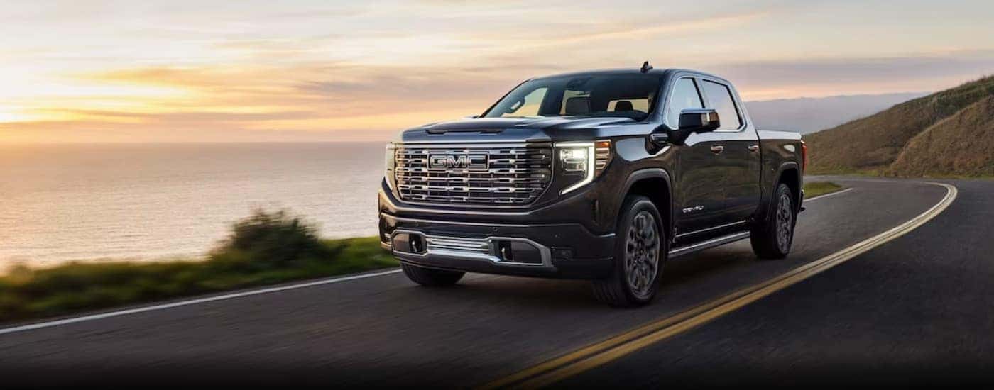 A gray 2024 GMC Sierra 1500 for sale is shown driving on a highway.