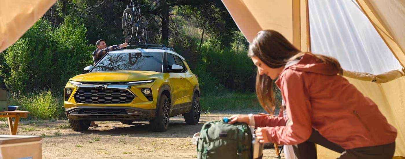 A yellow 2024 Chevy Trailblazer ACTIV is shown parked near a person in a tent.