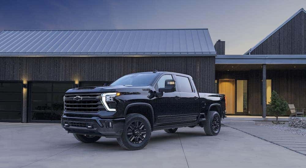 A black 2024 Chevy Silverado 2500 HD High Country is shown from the front at an angle after leaving a Chevy dealer near Champaign.