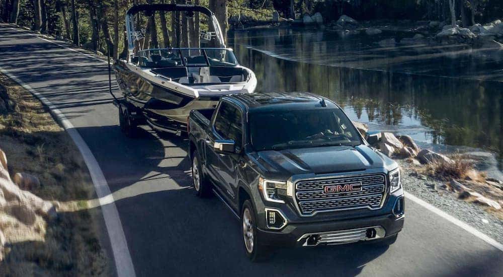 A black 2022 GMC Sierra 1500 is shown towing a boat after visiting a used GMC dealer.