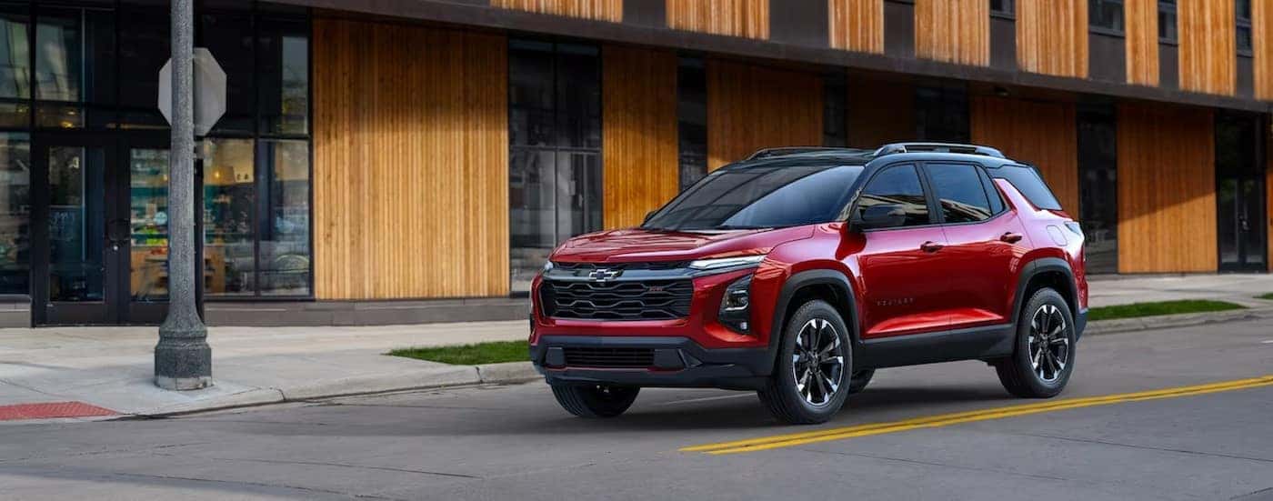 A red 2025 Chevy Equinox RS is shown stopped at a stop sign after visiting a Chevy dealer near Bloomington.