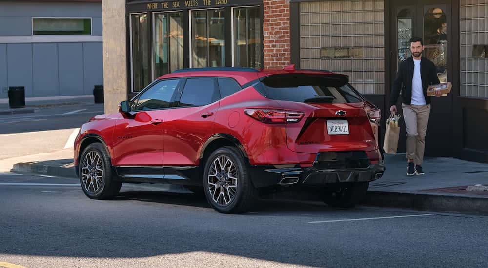 Rear view of a red 2025 Chevy Blazer parked by a city curb.