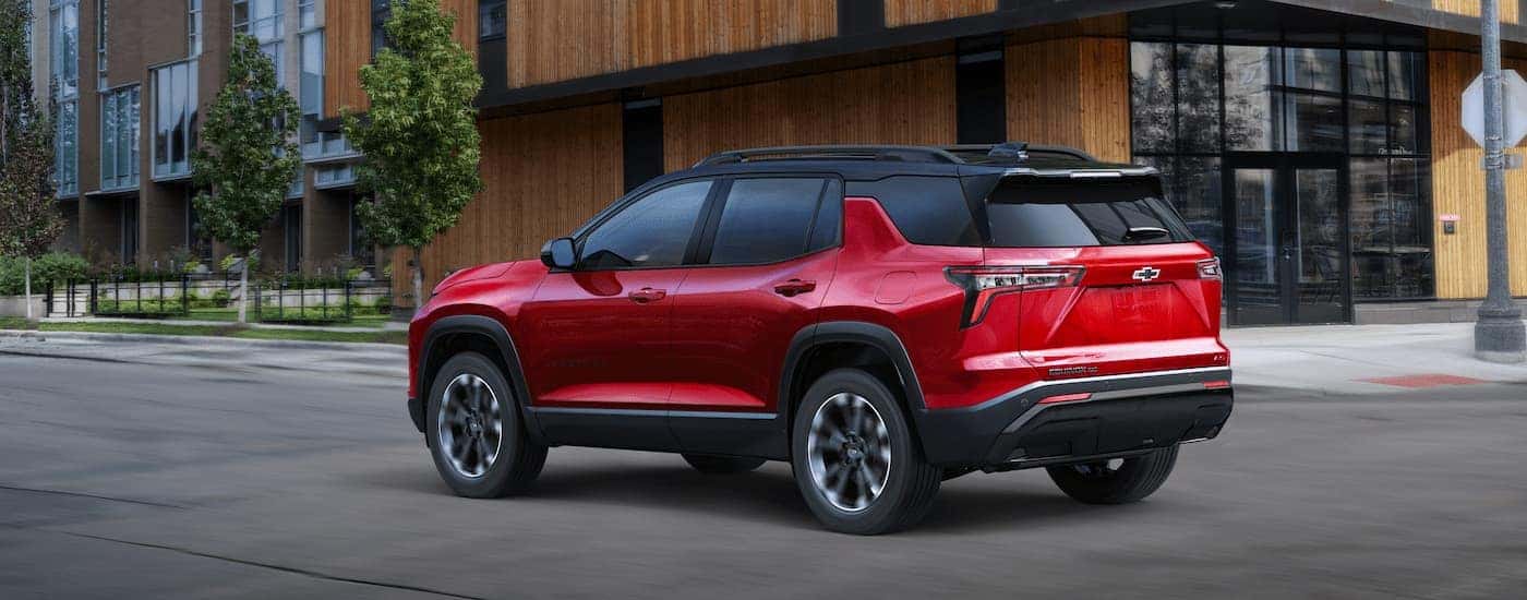 A red 2025 Chevy Equinox RS is parked on a driveway in front of a garage.